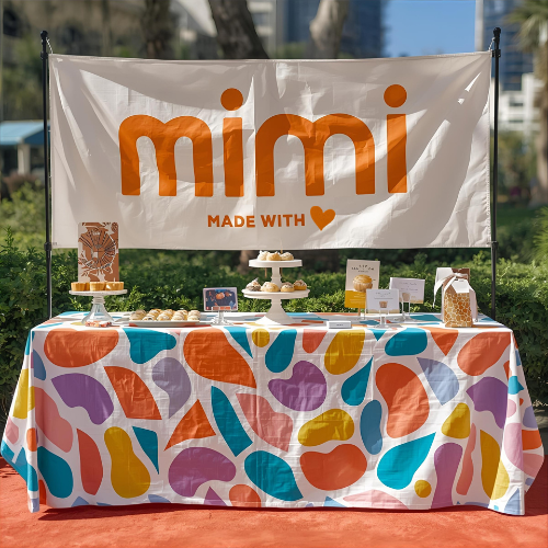 Colorful tablecloth with a 'mimi' banner at an outdoor event
